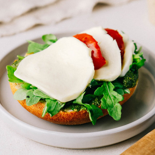 Knolli Italia 1/2 ﻿Halbes Kartoffelbrötchen belegt mit Pesto Basilikum, marinierten Tomaten, Mozzarella und frischem Rucola.